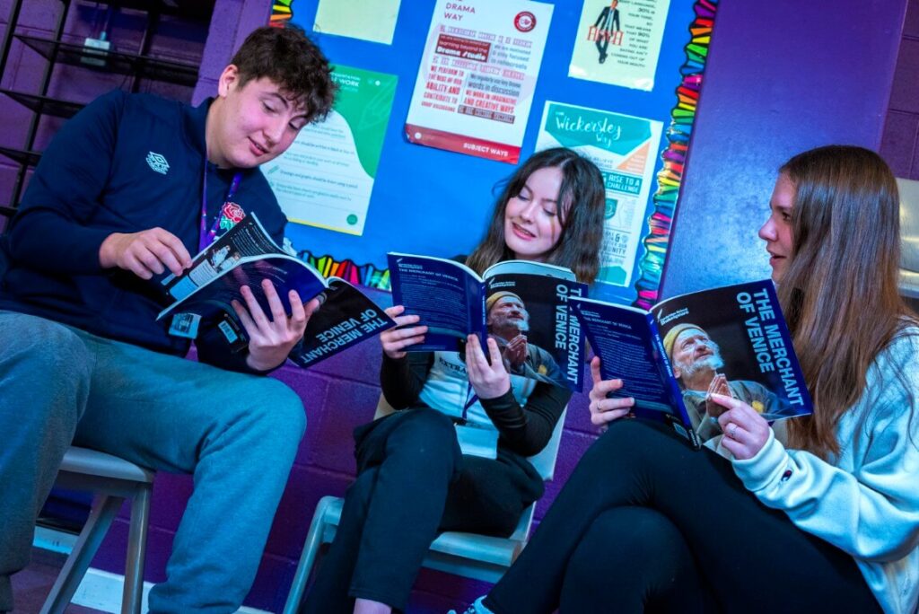 Three students (1 male, 2 female), sat studying a drama text