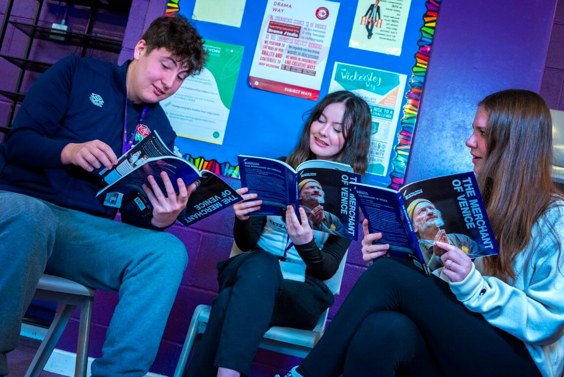 Three students (1 male, 2 female), sat studying a drama text